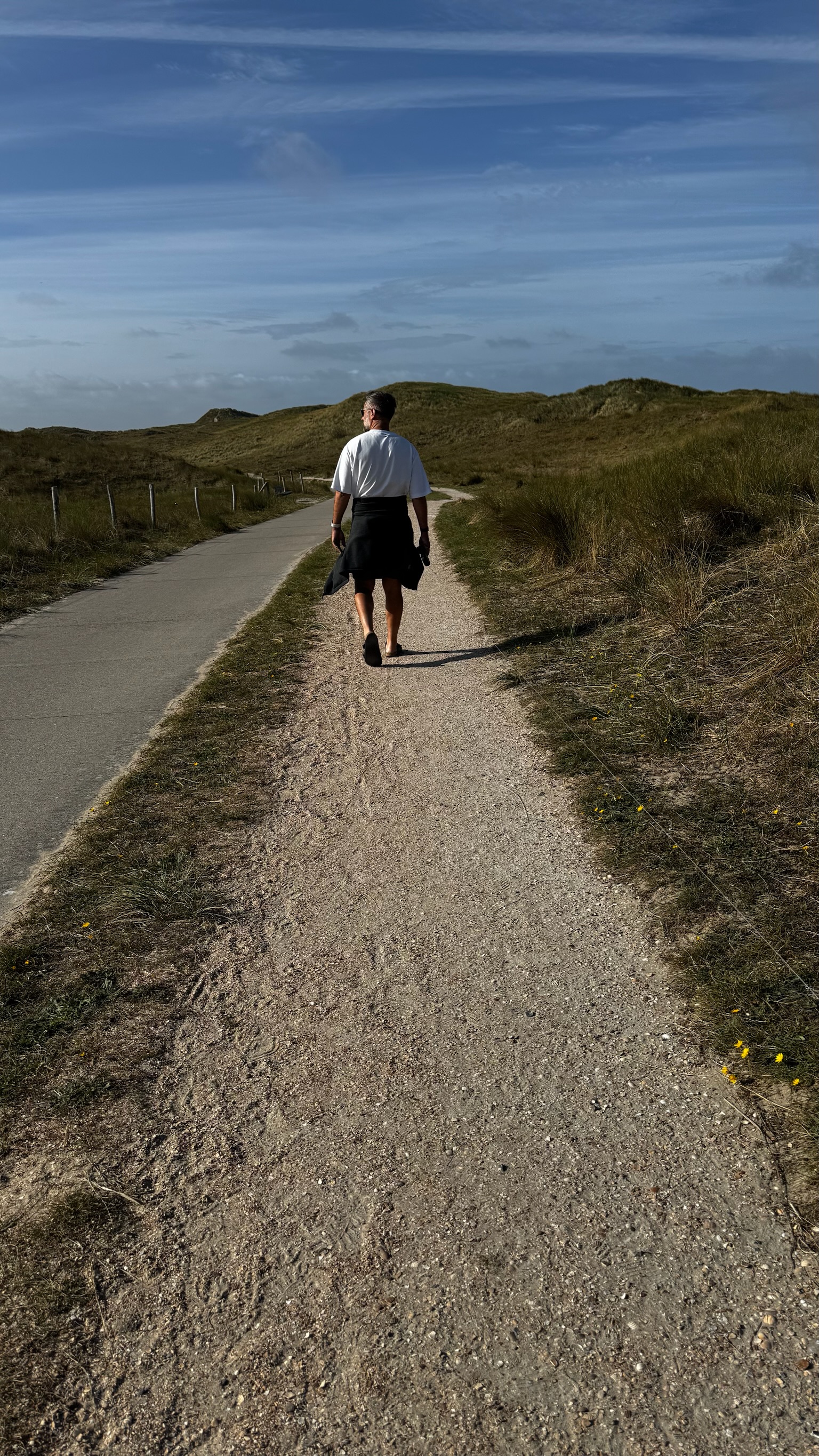 Sebastian Clauß auf einem Dünenweg, von hinten fotografiert